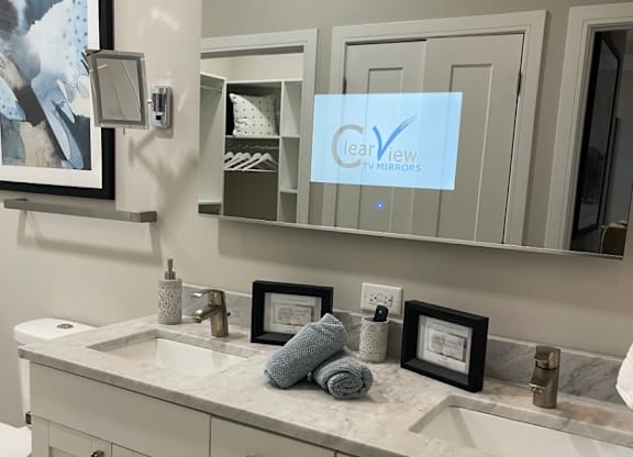 A bathroom with a white counter top and a mirror with a LeaView logo on it.