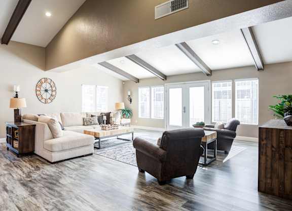 A living room with a white sofa, a brown armchair, and a wooden side table.