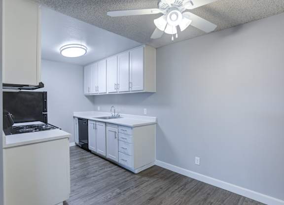 A kitchen with white cabinets and a black fridge.
