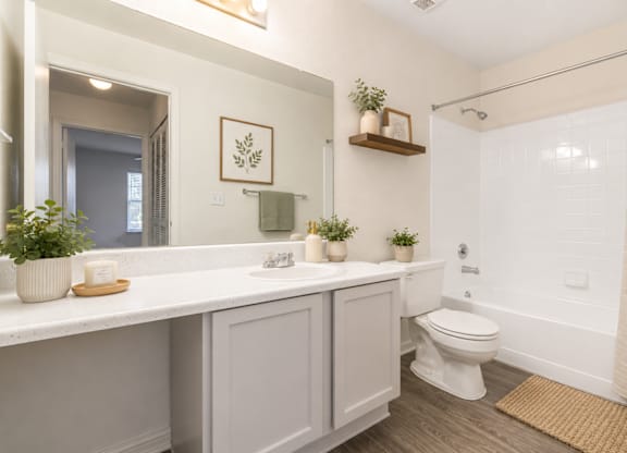 A white bathroom with a toilet, sink, and mirror.
