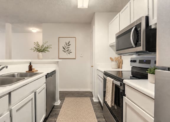 A kitchen with white cabinets and black countertops.