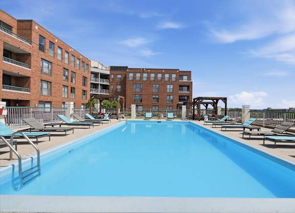 A large rooftop swimming pool surrounded by sun loungers and buildings.