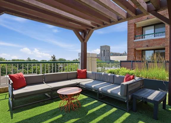 A rooftop patio with a couch, table and chairs under a roof.