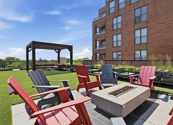 A rooftop patio with red and blue Adirondack chairs and a fire pit.