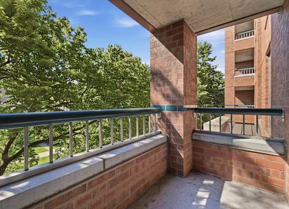 A balcony with a metal railing and a brick wall.