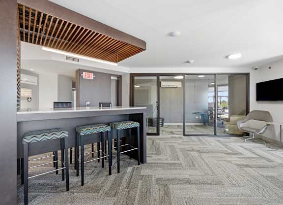 Main room of the business center with a community work table and conference rooms in the background.