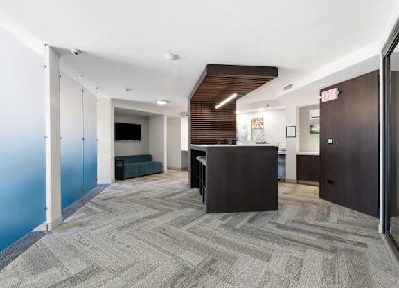 Main room of the business center with a community work table, conference rooms on the sides, and printer in the background.