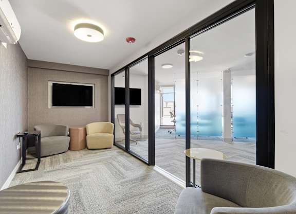 A conference room in the business center with TV and assorted seating.
