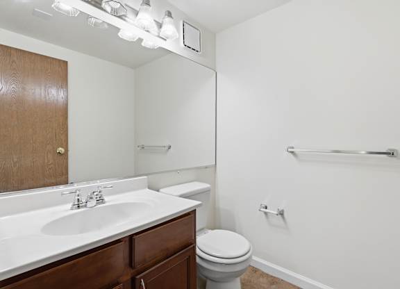 A white bathroom with a toilet, sink, and mirror.