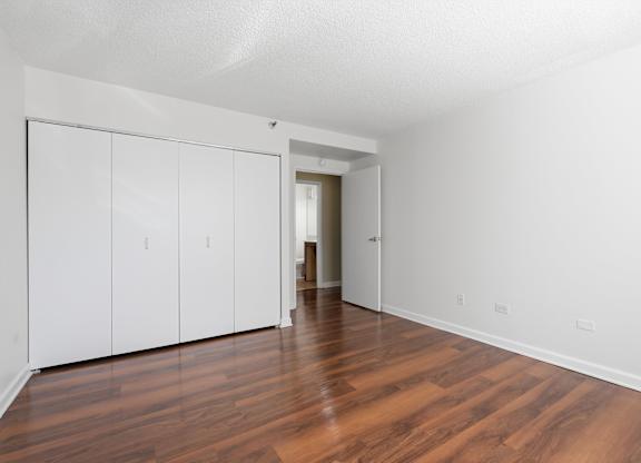 A bedroom with wooden flooring and closet.