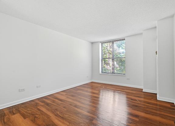 A bedroom with wooden flooring and window.
