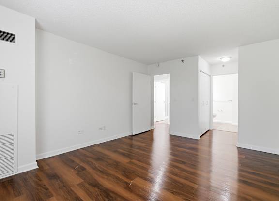 A bedroom with wooden flooring and walk in closet.