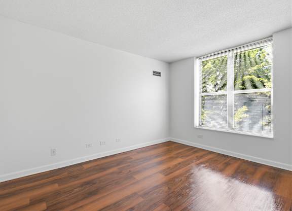 A bedroom with wooden flooring and window.