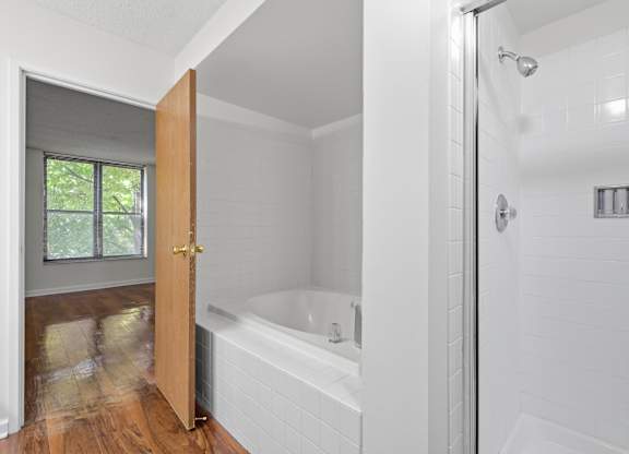 A white bathroom with standing glass shower and separate jacuzzi tub.