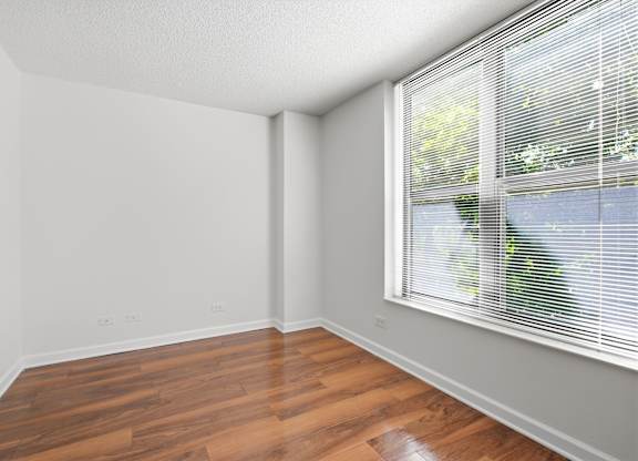 A den with wooden floors and large window attached to a bedroom.