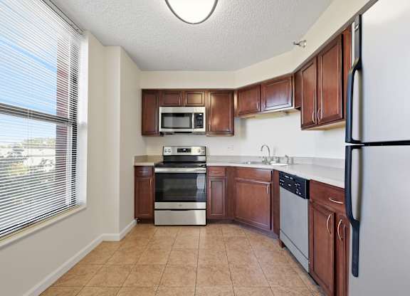 A kitchen with brown cabinets and a stainless steel appliances: microwave, stove, dishwasher, and fridge.