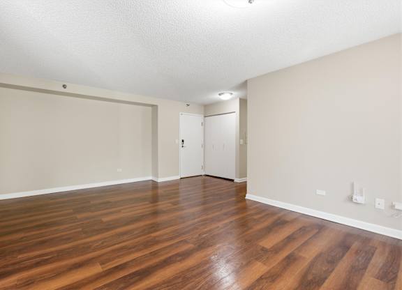 A living room with wooden floors and front hall closet.