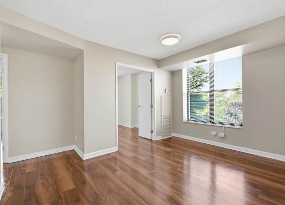 a living room with wooden floors and window.