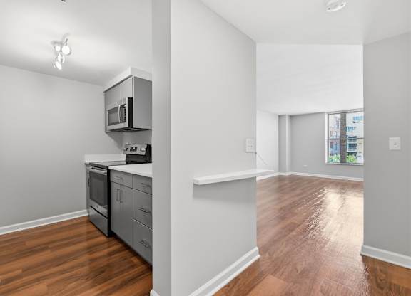 A renovated kitchen with a stainless steel refrigerator, microwave, oven, and 2-in-1 washer/dryer.
