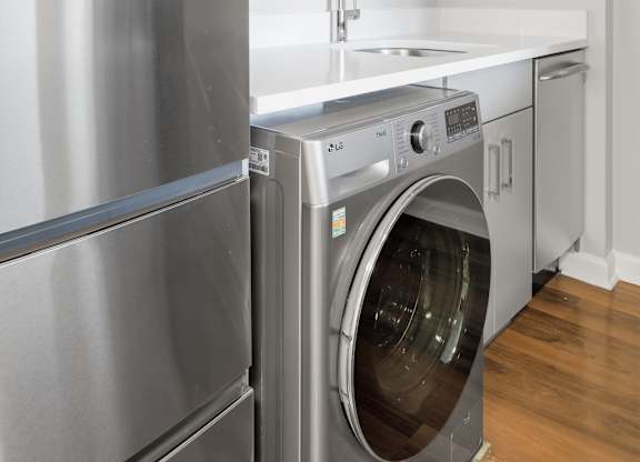 A renovated kitchen with a stainless steel refrigerator and 2-in-1 washer/dryer.