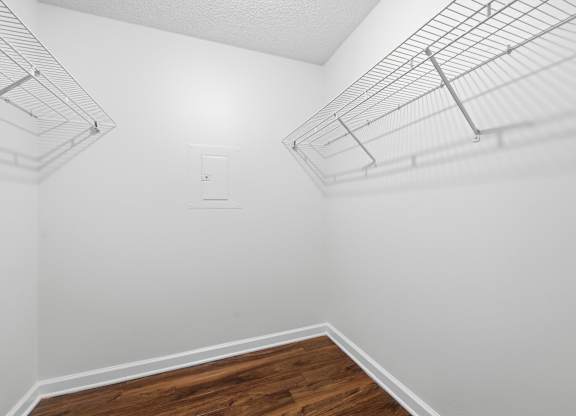 A white wall with a wooden floor and a metal shelf.