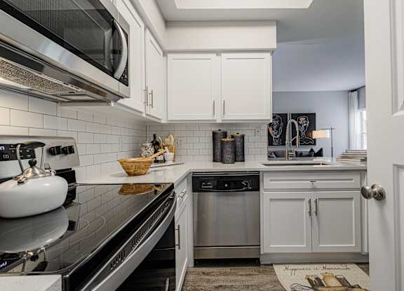 a kitchen with white cabinets and appliances and a black counter top