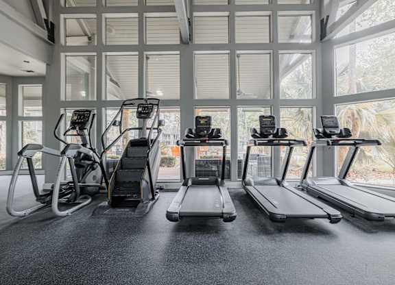 the gym at the monarch club has cardio equipment and a large window