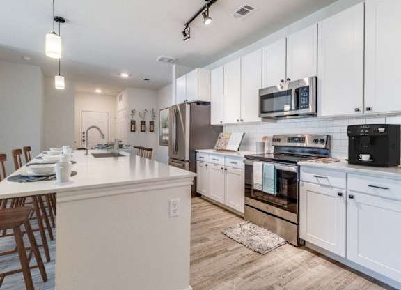 a large kitchen with white cabinets and stainless steel appliances