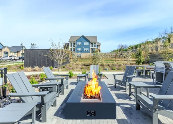 A fire pit in the middle of a patio surrounded by chairs.