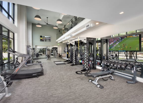 a gym with cardio machines and weights and a large tv