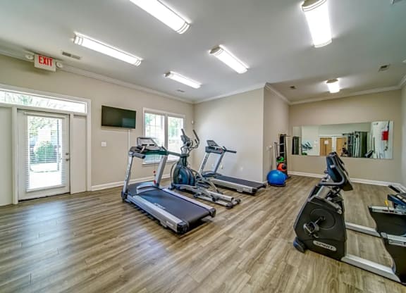 a gym with treadmills and weights and a tv