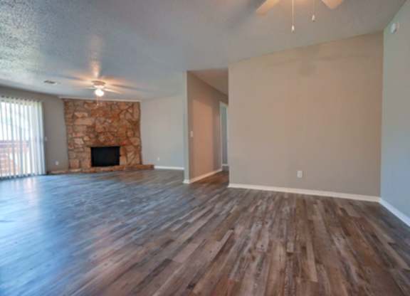 A room with wooden floors and a stone fireplace.