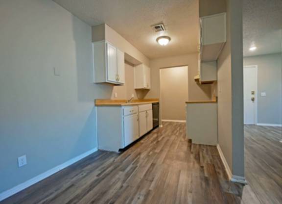 A kitchen with white cabinets and a wooden floor.