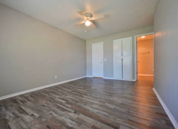 A room with a ceiling fan and wood flooring.