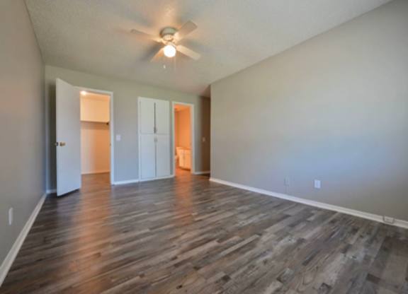 A room with a ceiling fan and wooden flooring.