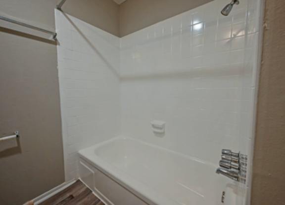 A white bathtub in a bathroom with a white shower curtain.