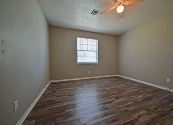 A room with wooden flooring and a window.