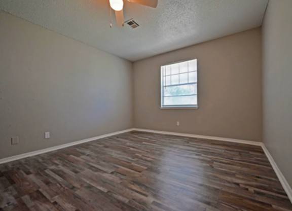 A room with wooden flooring and a window.