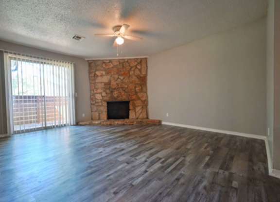 A room with a stone fireplace and wood flooring.