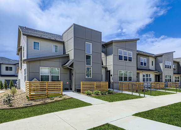 A row of modern houses with a sidewalk in front.