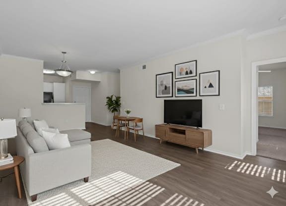 A living room with a white couch, a wooden side table, a television, and a rug.