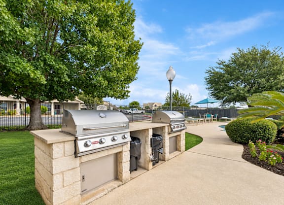 A BBQ grill is on a stand in a backyard.