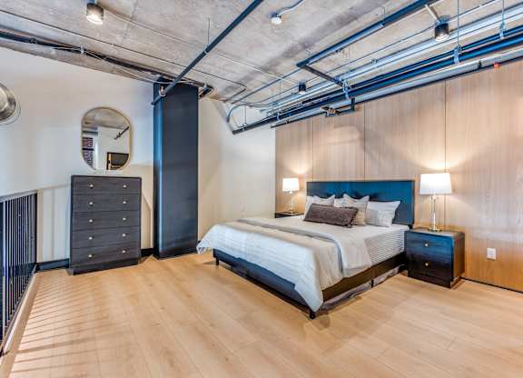 A bedroom with a bed, nightstands, and a wooden floor.