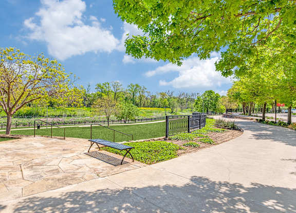 A park with a bench and a fence.