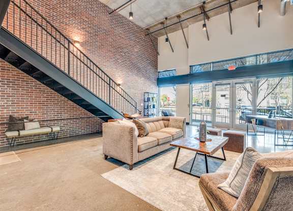 A living room with a couch, a coffee table, and a staircase.