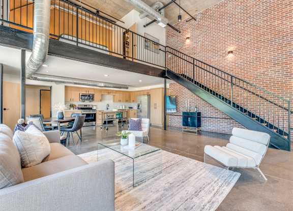 A living room with a grey couch and a glass coffee table.