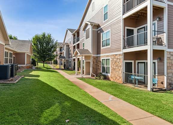 A sunny day at a residential apartment complex with a well-maintained lawn and pathway.