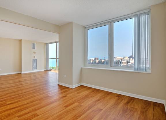 A room with wooden floors and a large window overlooking a cityscape.