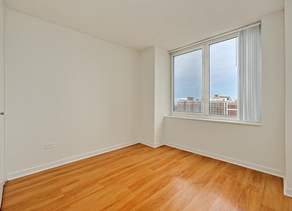 A room with wooden floors and a window overlooking a cityscape.