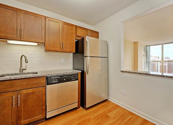 A kitchen with a refrigerator, sink, and stove.